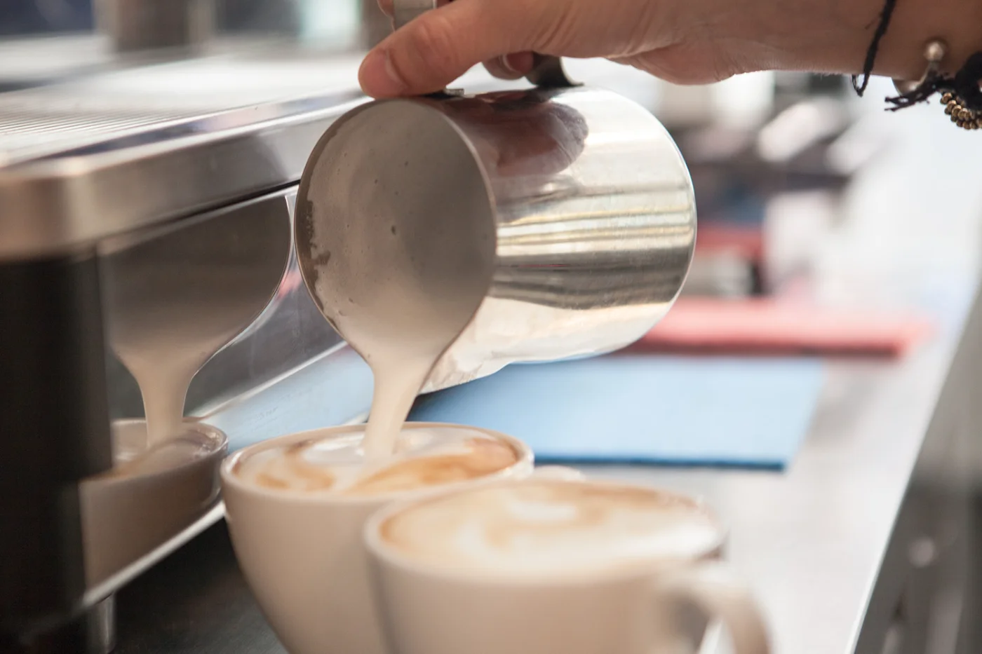 Barista gießt Latte Art in zwei Cappuccino